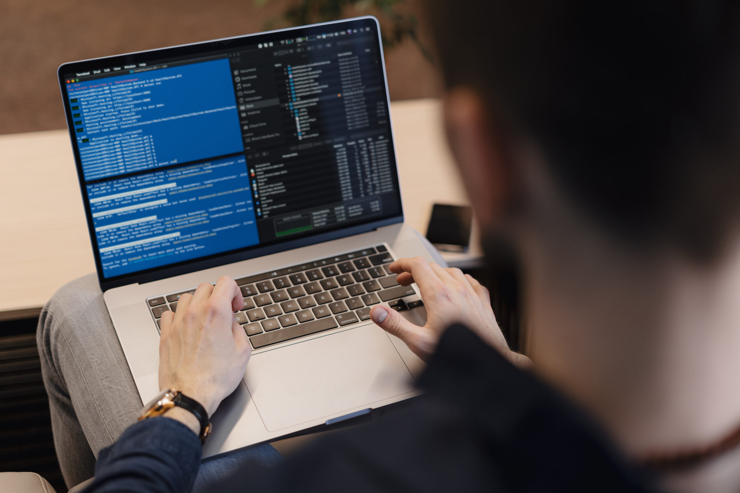 Eine Mann tippt auf einem Laptop auf dem Code zu sehen ist